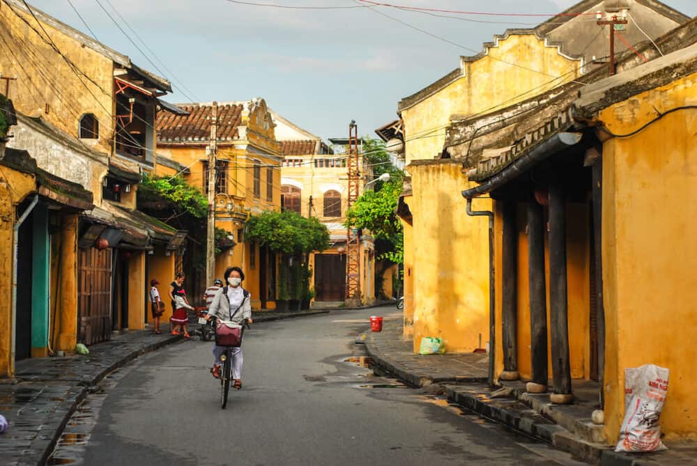 HOI AN VIETNAM : An unidentified biker rider passing an ancient house in Hoi An town the World's cultural heritage and famous attraction in Quang Nam Vietnam