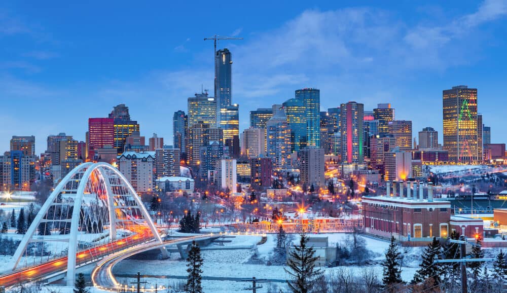 Edmonton downtown Winter skyline just after sunset at the blue hour showing Walterdale Bridge across the frozen, snow-covered Saskatchewan River and surrounding skyscrapers. Edmonton is the capital of Alberta, Canada.