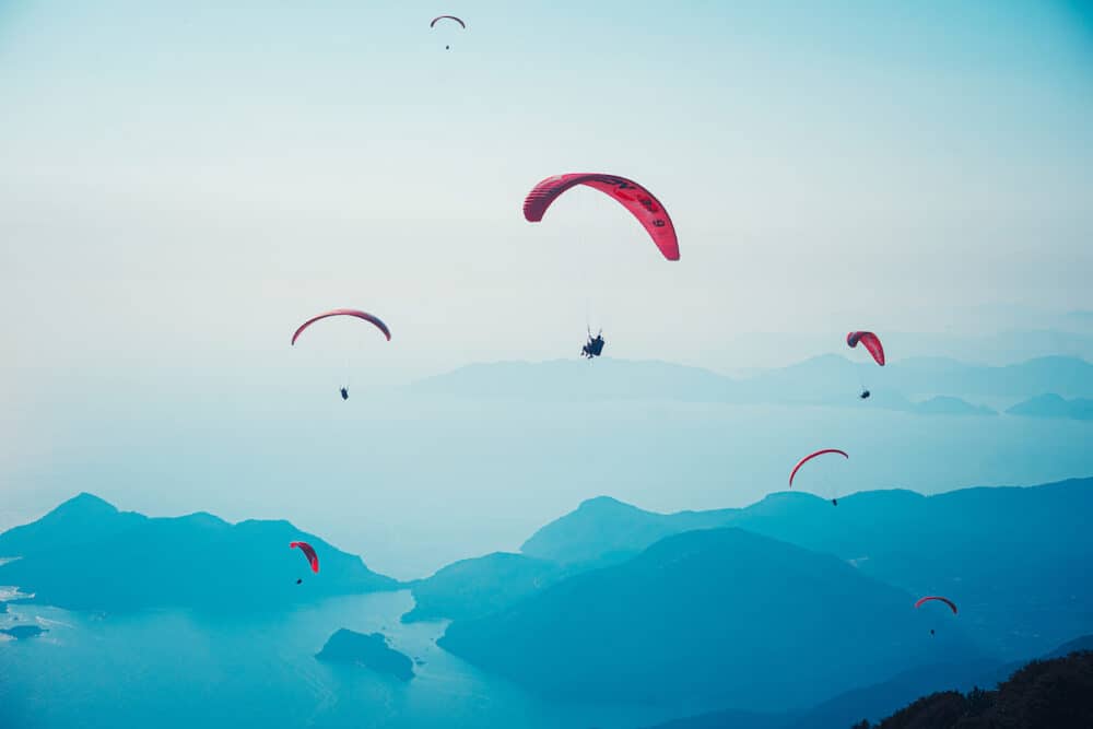 Fethiye, Mugla / Turkey Paragliding in the sky. Paraglider tandem flying over the sea with mountains at sunset. Aerial view of paraglider and Blue Lagoon in Oludeniz, Mugla, Turkey.