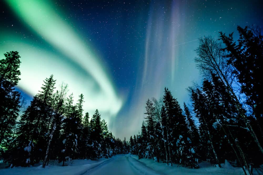 Northern lights Aurora Borealis activity over wooden cottage in winter Finland, Lapland