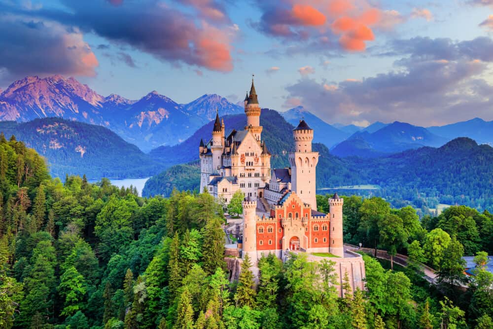 Neuschwanstein Castle, Germany. Front view of the castle and the Bavarian Alps at sunrise.