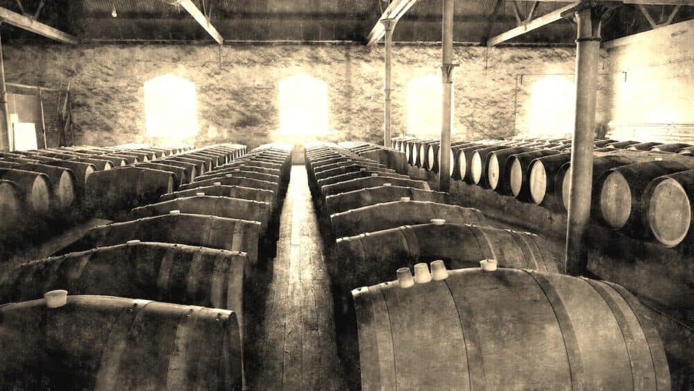 Aged photo of Historical Wine Cellar featuring rows of wine barrels in winery after vintage and harvest