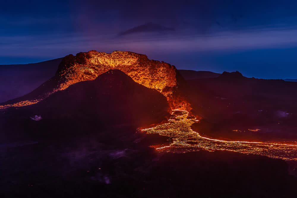Lateral flow of lava from the crater from the volcanic eruption in Iceland. Crater from Fagradalsfjall volcano at night to the blue sky. Volcano on the Reykjanes peninsula in the GeoPark