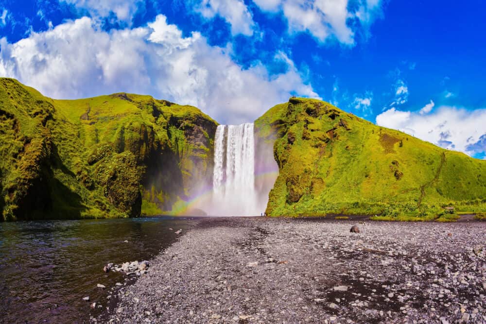 Iceland, waterfall Skogafoss summer, clouds of mist. Huge picturesque waterfall flowing from under a giant glacier