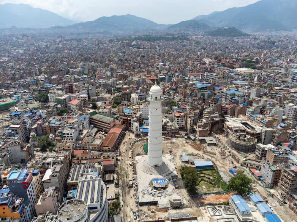 An aerial view of the city of Kathmandu, Nepal on a cloudy day with the Darahara Tower in the the foreground.