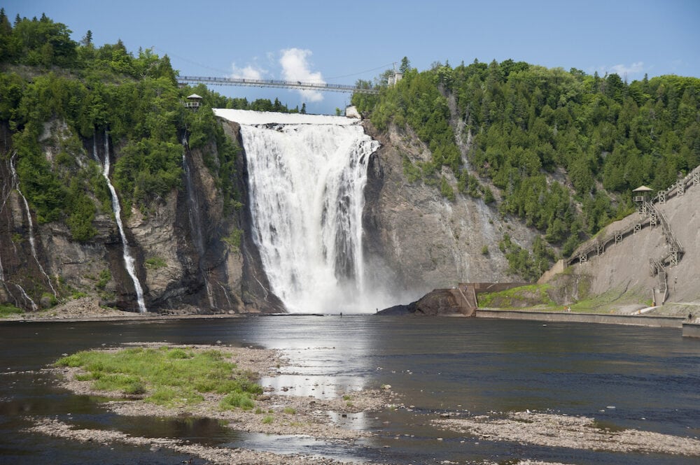 Fishermen in the river are dwarfed by the spectacular height of Montmorency Falls