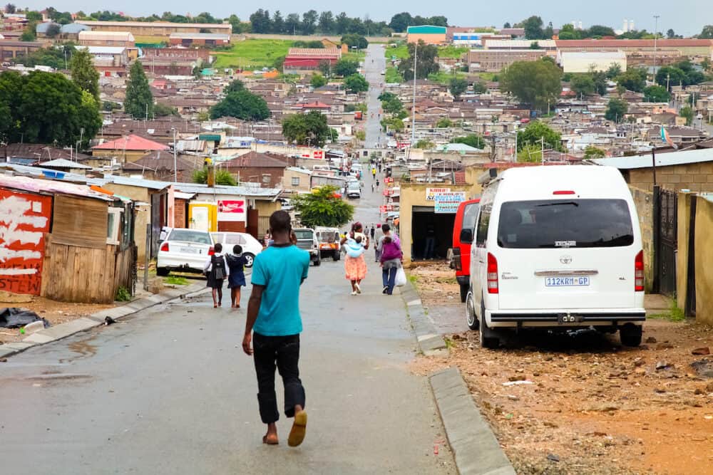 Johannesburg, South Africa - : African people walking down a main road in Alexandra township, a formal and informal settlement
