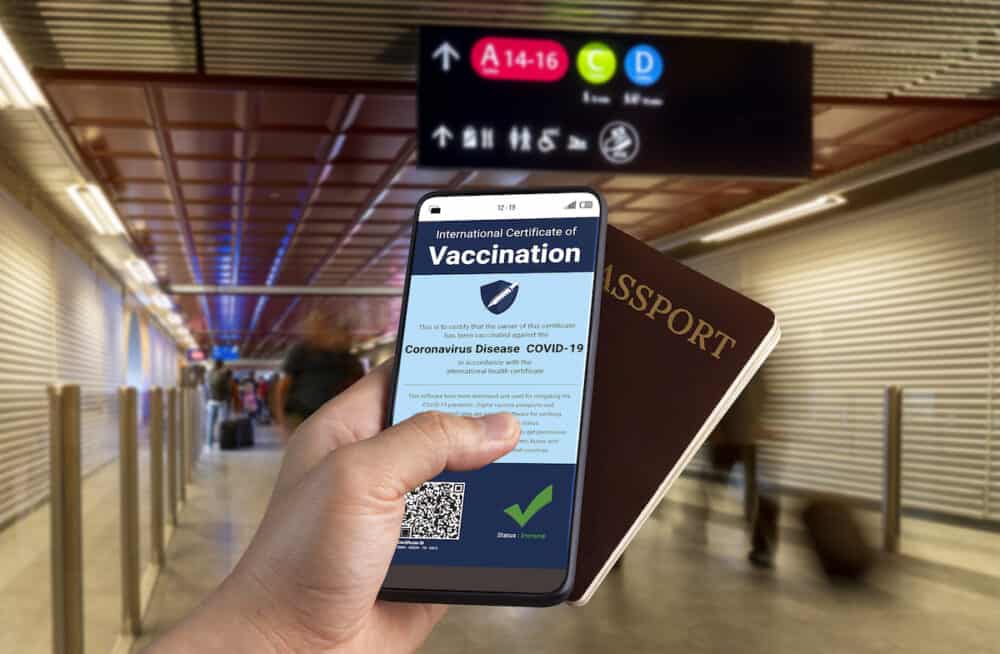 Traveler holds vaccine passport certificate to show COVID 19 vaccination status . The digital health certificate is required for international travel during coronavirus pandemic .