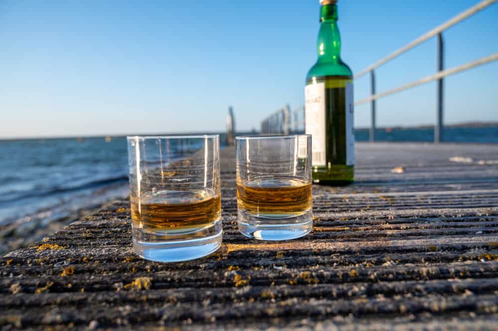 Drinking single malt Scotch whisky at sunset with sea, ocean or river view, private whisky distillery tours in Scotland, UK