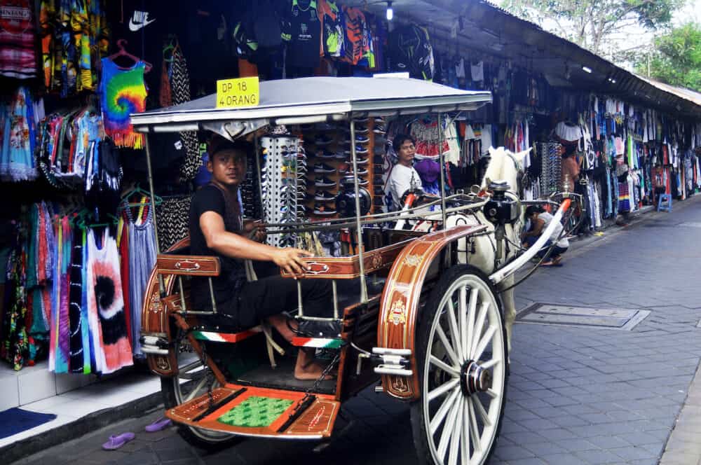 BALI, INDONESIA - Balinese people riding horse drawn carriage cart for service tour Indonesian people and foreign travelers travel visit at Kuta Beach 