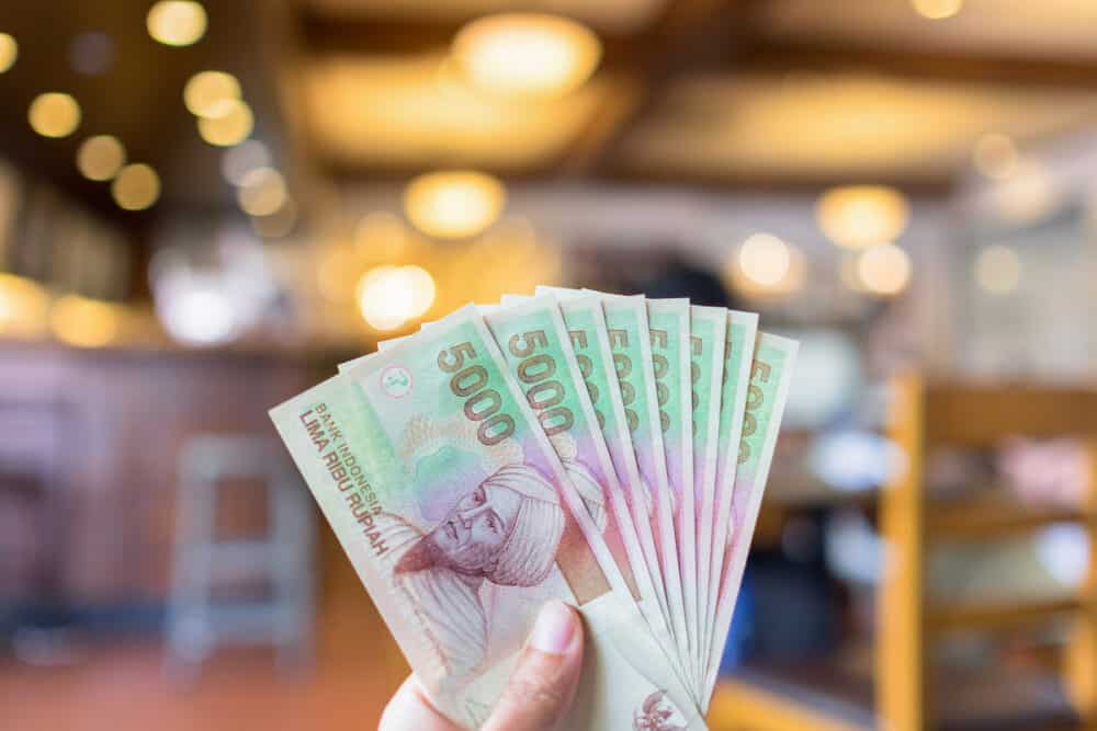 Indonesian rupiah money in hand with bokeh background in coffee shop Bali Island Indonesia