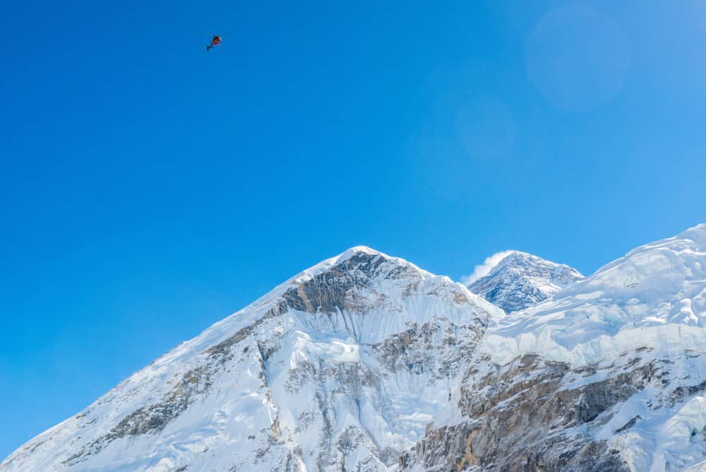 Scenic flight or rescue helicopter flying over Mt.Everest (8,848 m) the highest mountains peak in the world in Sagarmatha national park, Nepal.
