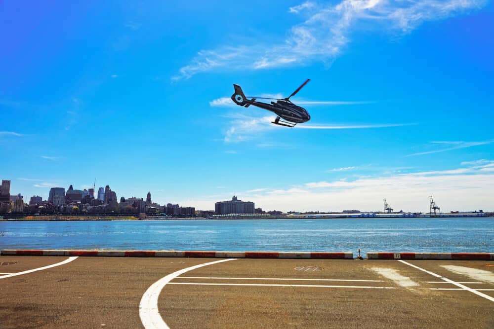 New York, USA - Black Helicopter taking off from helipad in Lower Manhattan in New York, the US, on East River. Pier 6. East River and skyscrapers of Brooklyn on the background