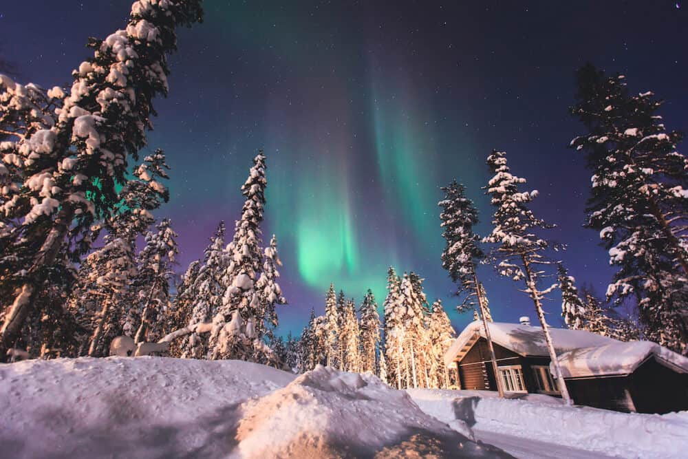 Beautiful picture of massive multicolored green vibrant Aurora Borealis Aurora Polaris also know as Northern Lights in the night sky over winter Lapland landscape