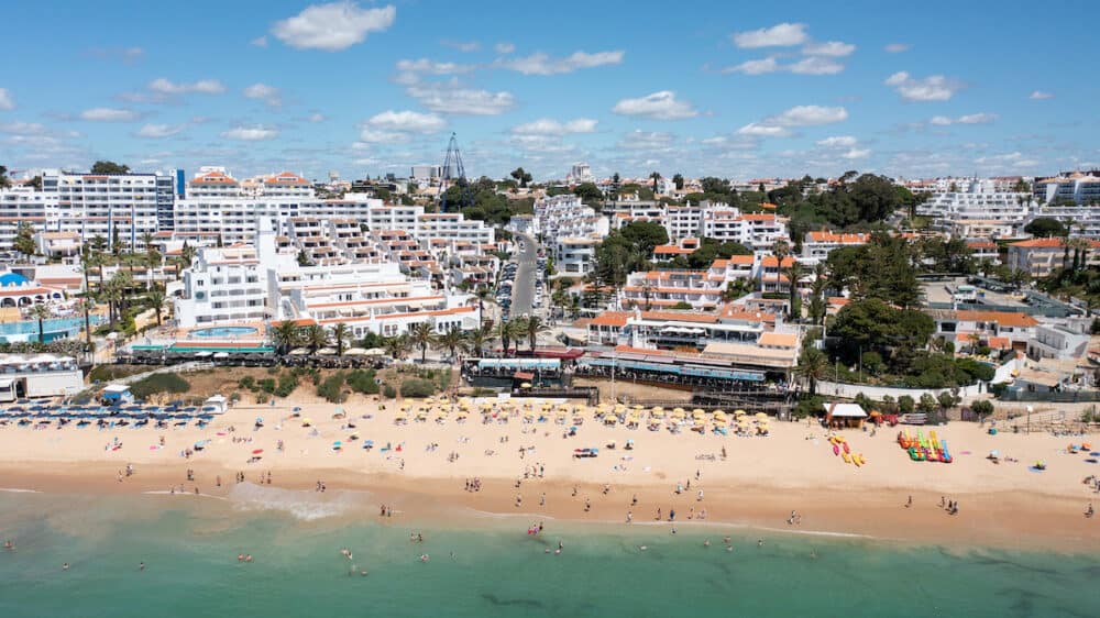 Aerial photo of the beautiful town in Albufeira in Portugal showing the Praia da Oura golden sandy beach, with hotels and apartments in the town, taken on a summers day in the summer time.