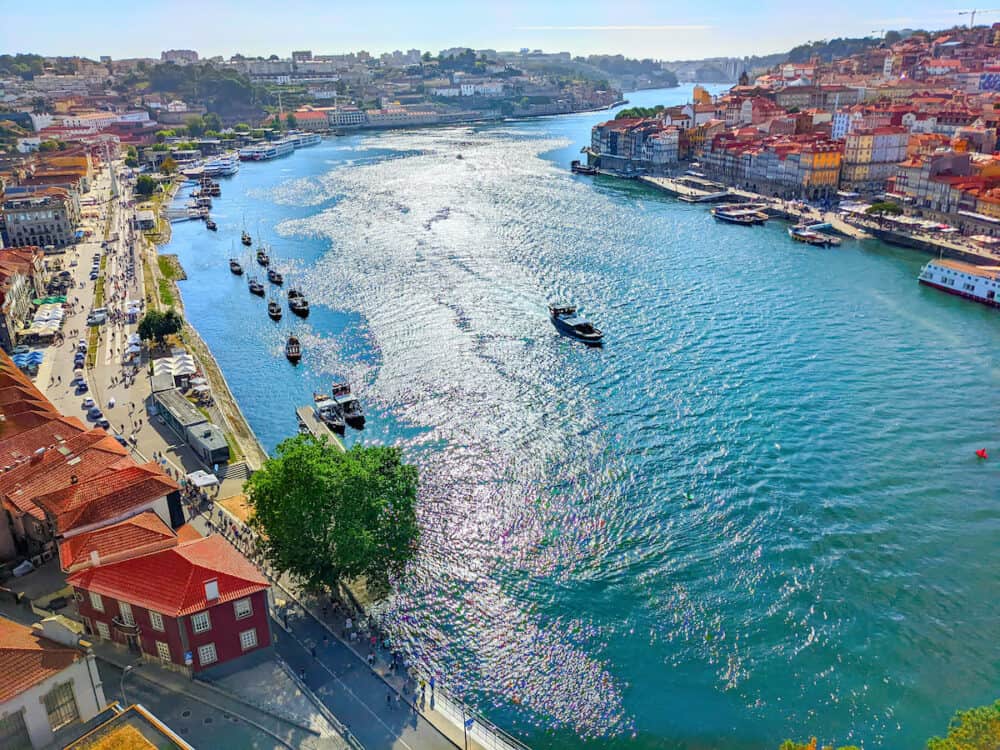 Aerial view of Porto riverbanks cityscape and cruise boats at Douro river in bright sunshine from Dom Luis bridge, Porto, Portugal