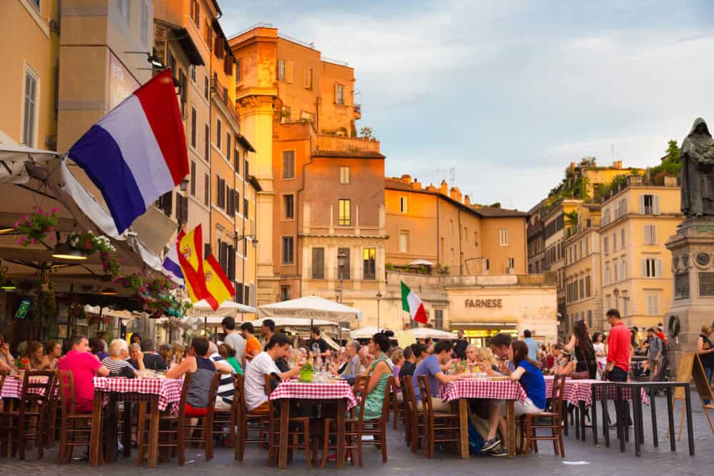 People having aperitif which in Italy traditionally includes free all you can eat buffet of pizzas and pastas, on Piazza Campo Dè Fiori in Rome in Italy.