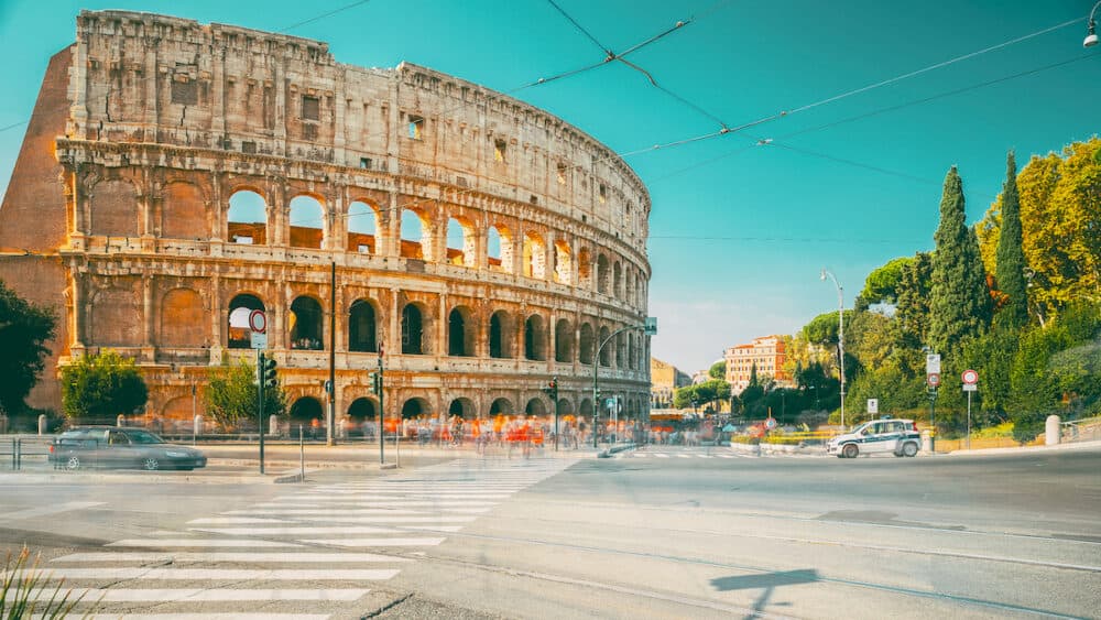 Rome, Italy. Colosseum. Traffic Near Flavian Amphitheatre. Famous Touristic World Landmark. Bright Blue Sky. Unesco. Travel Rome.