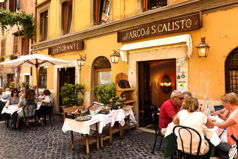 Unidentified people eating traditional italian food in outdoor restaurant in Trastevere district in Rome Italy.