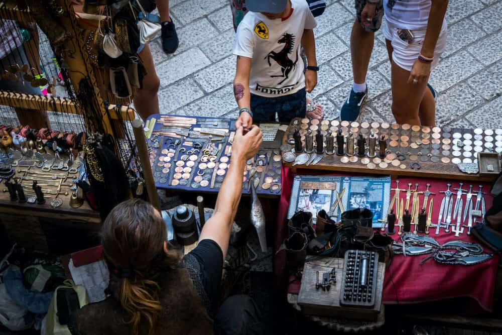 Merchant selling handmade antique souvenir to a child in Dubrovnik s street market. Dubrovnik is one of the most famous travel destination in Croatia.