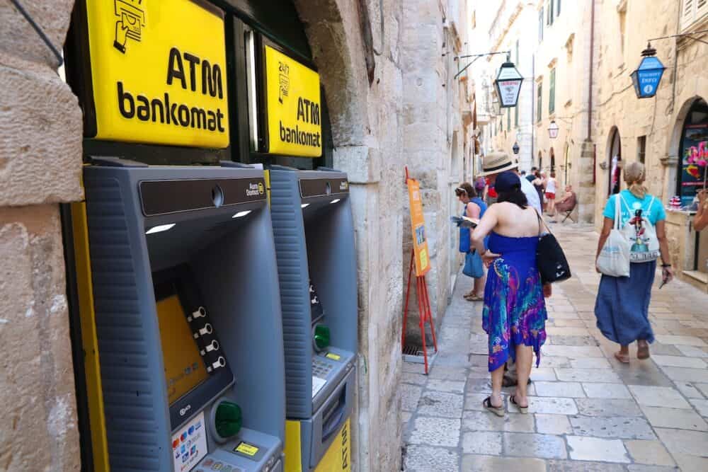Tourists walk by ATMs at a shopping street in Dubrovnik Old Town, a UNESCO World Heritage Site.