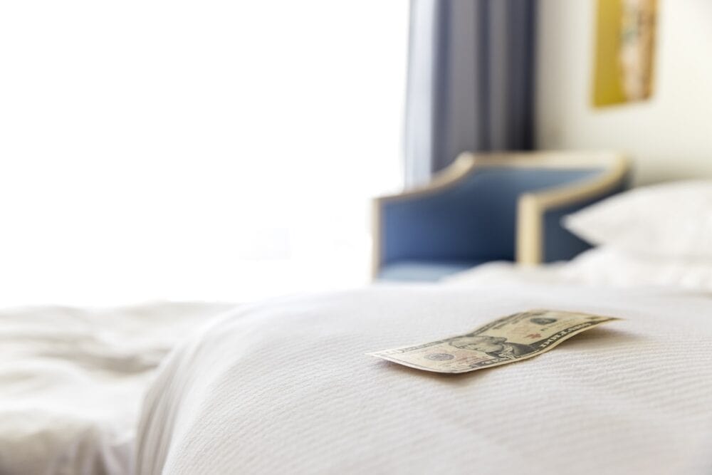 Traditional tips is laying on the corner of the bed in hotel room. Dollar or euro money tips to thank the room cleaner for good service. Grateful vacationers at the Egypt resort. High quality photo