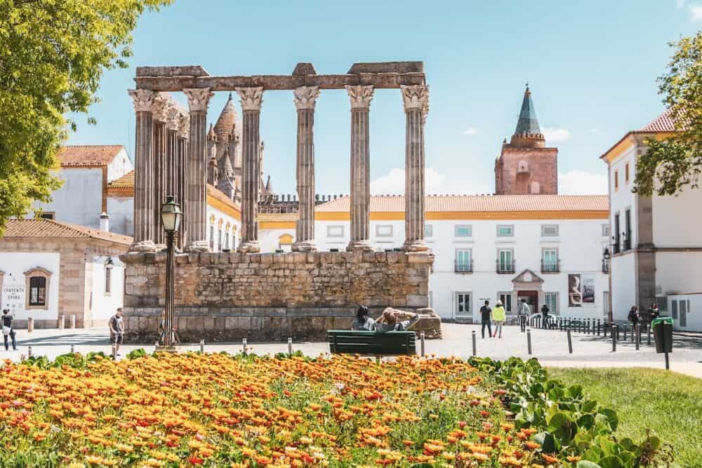 architectural detail of the Roman temple of Evora in Portugal or Temple of Diana in front of which people are walking on a spring day. It is a UNESCO World Heritage Site
