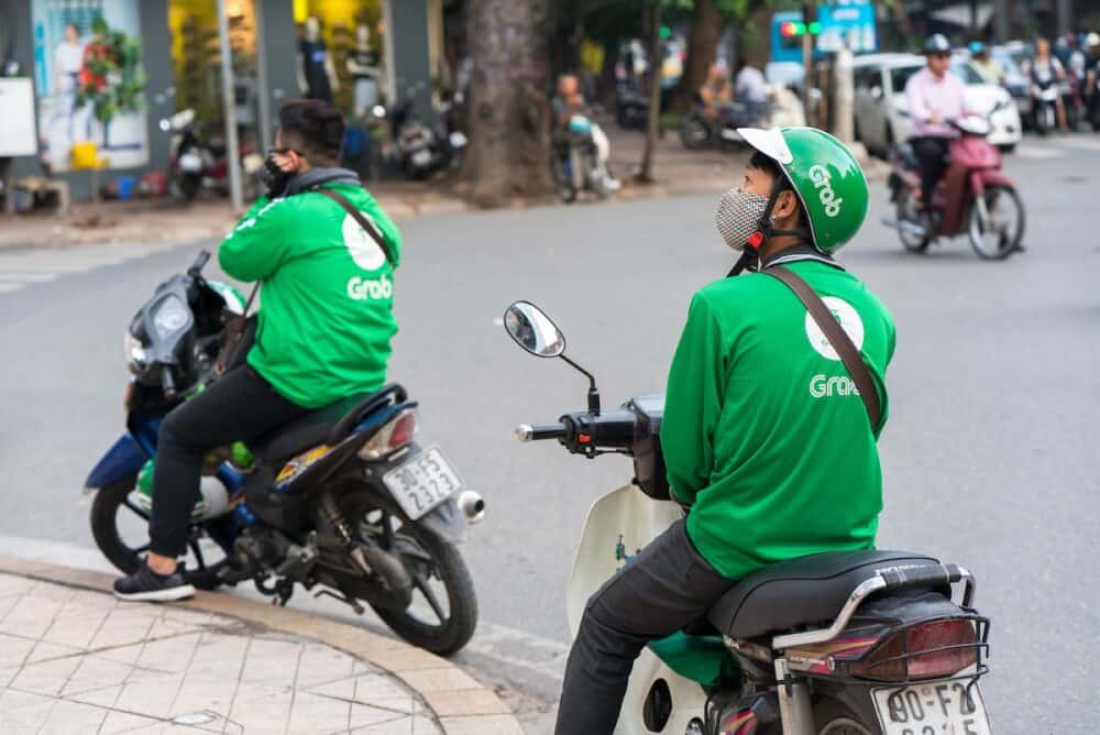 Grab motorbike driver waiting for customer on Ba Trieu street. Entered Vietnam in 2014, Grab growing fast due to cheap fare and safer than traditional motorbike taxi