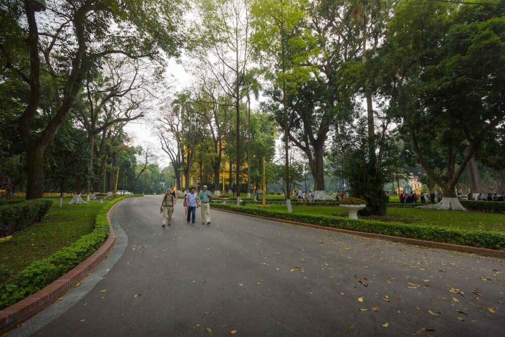  Tourists and Tour guide walking in the garden at the Presidential Palace Area, Hanoi, Vietnam