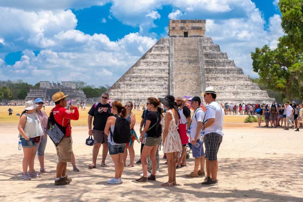 Tourists hear an explanation from their guide next to the Pyramid of Kukulkan at Chichen Itza