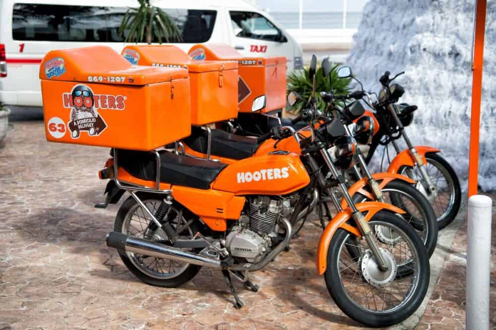 Cozumel Mexico - hooters motorcycles of orange color parked on street outdoor. Food delivery service concept