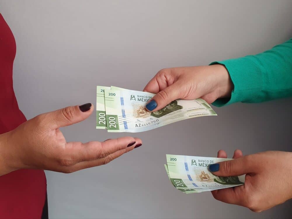 women hands paying and receiving Mexican money