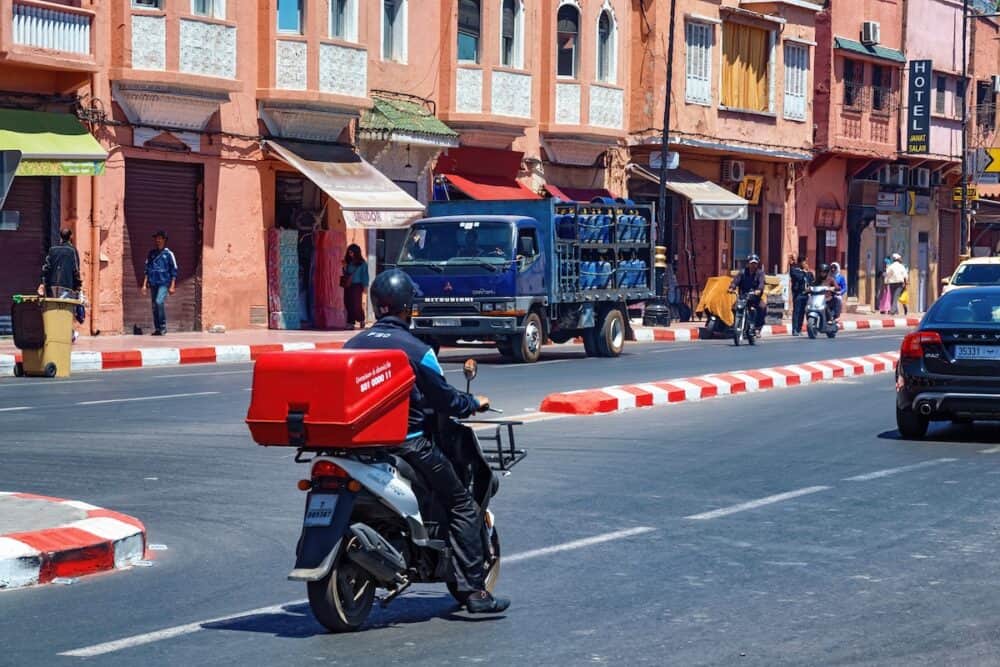 MARRAKESH, MOROCCO -  Courier rides a motobike with home delivery box on the road in Marrakech.