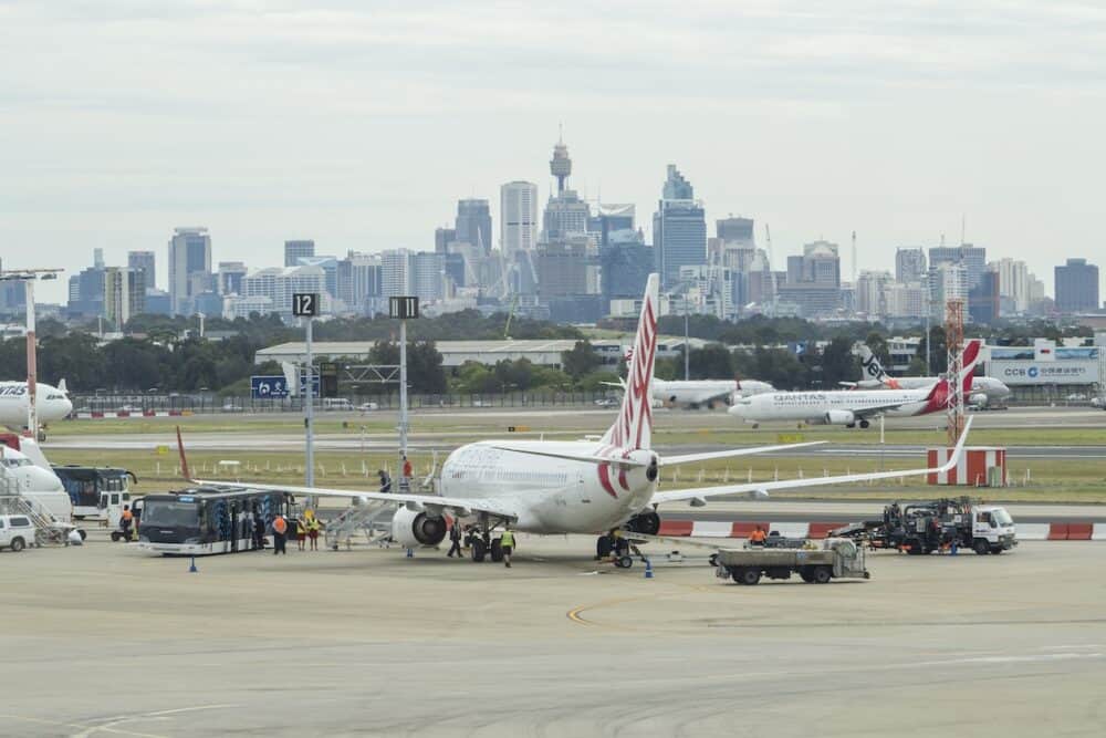 Sydney, Australia -View of passengers getting off an airplane at the Sydney Airport, with view of CBD in the background. It is the busiest airport in Australia.
