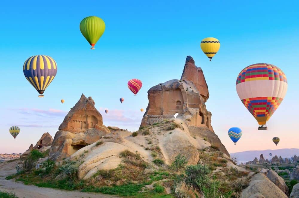 Hot air balloons flying over spectacular landscape of fairy chimneys carved in volcanic tuff by erosion. Cappadocia Turkey
