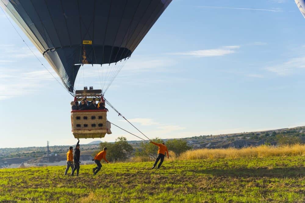 Cappadocia, Turkey. Unusual shot showing take-off of hot air ballon filled with tourists. Cappadocia - the most popular place for ballon traveling. Four professional workers taking care of save take-off. 