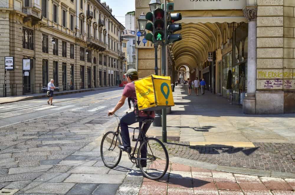  A worker from Glovo, home delivery company for food and drink. It is easy to notice them: the showy yellow duffel bag with the typical green logo.