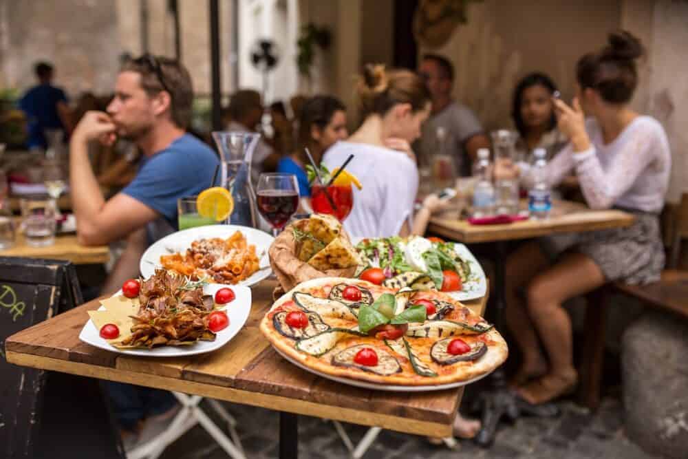 Unidentified people eating traditional italian food in outdoor restaurant in Trastevere district in Rome, Italy.
