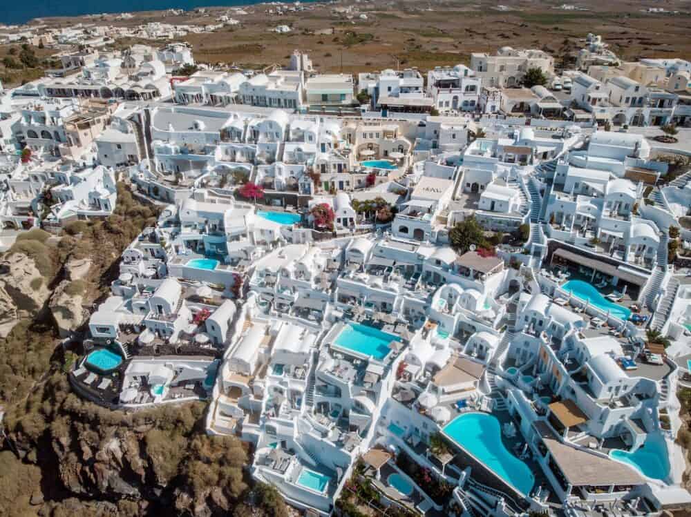Drone view over Santorini, aerial view over the whitewashed village of Oia with luxury vacation resort with infinity pools in Santorini Greece
