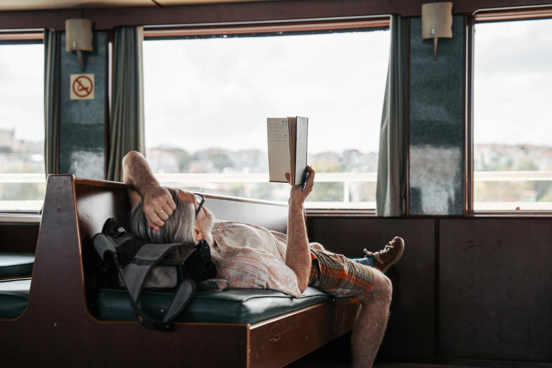 man reading a book lying down on a train
