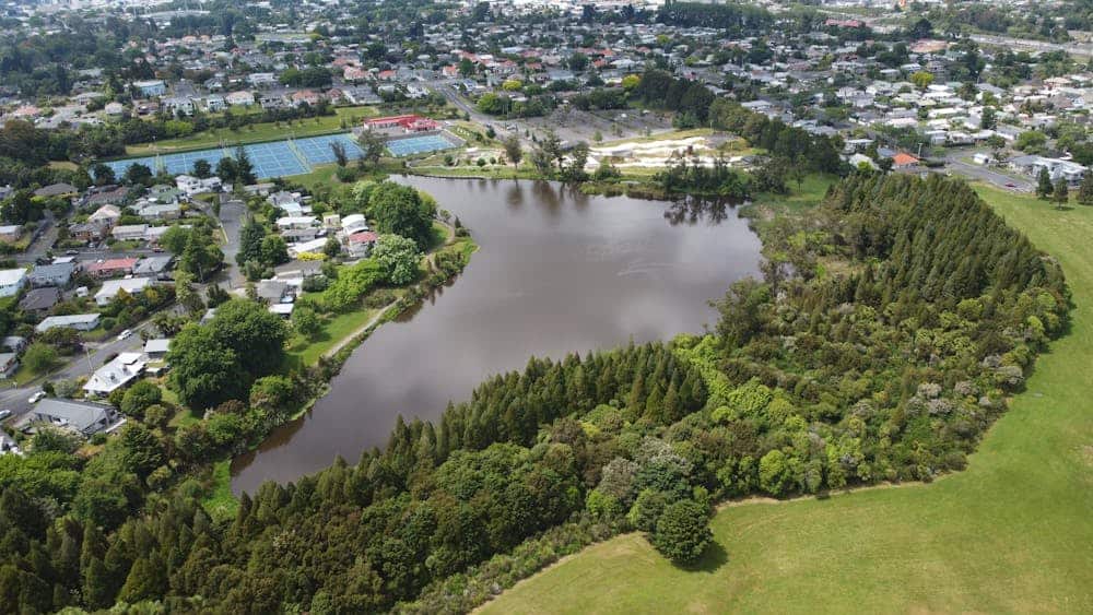 Aerial perspective of a lake surrounded by trees and residential houses in Hamilton, New Zealand.