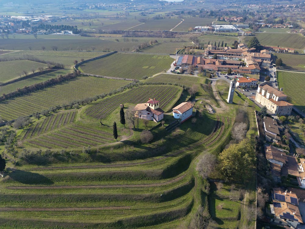 Aerial shot of a vineyard and small village in Brescia, Lombardy, Italy, showcasing rural landscape.