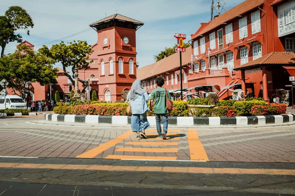 Tourists walk through Dutch Square, a vibrant historical landmark in Malacca, Malaysia.