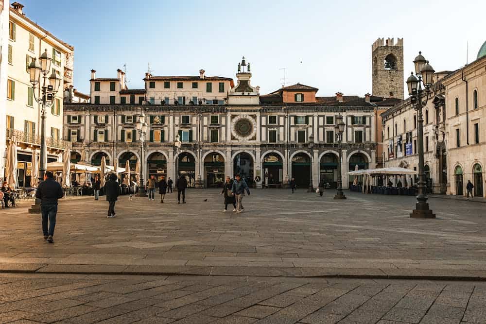 View of the Historic Piazza della Loggia in Brescia with people enjoying a sunny day.