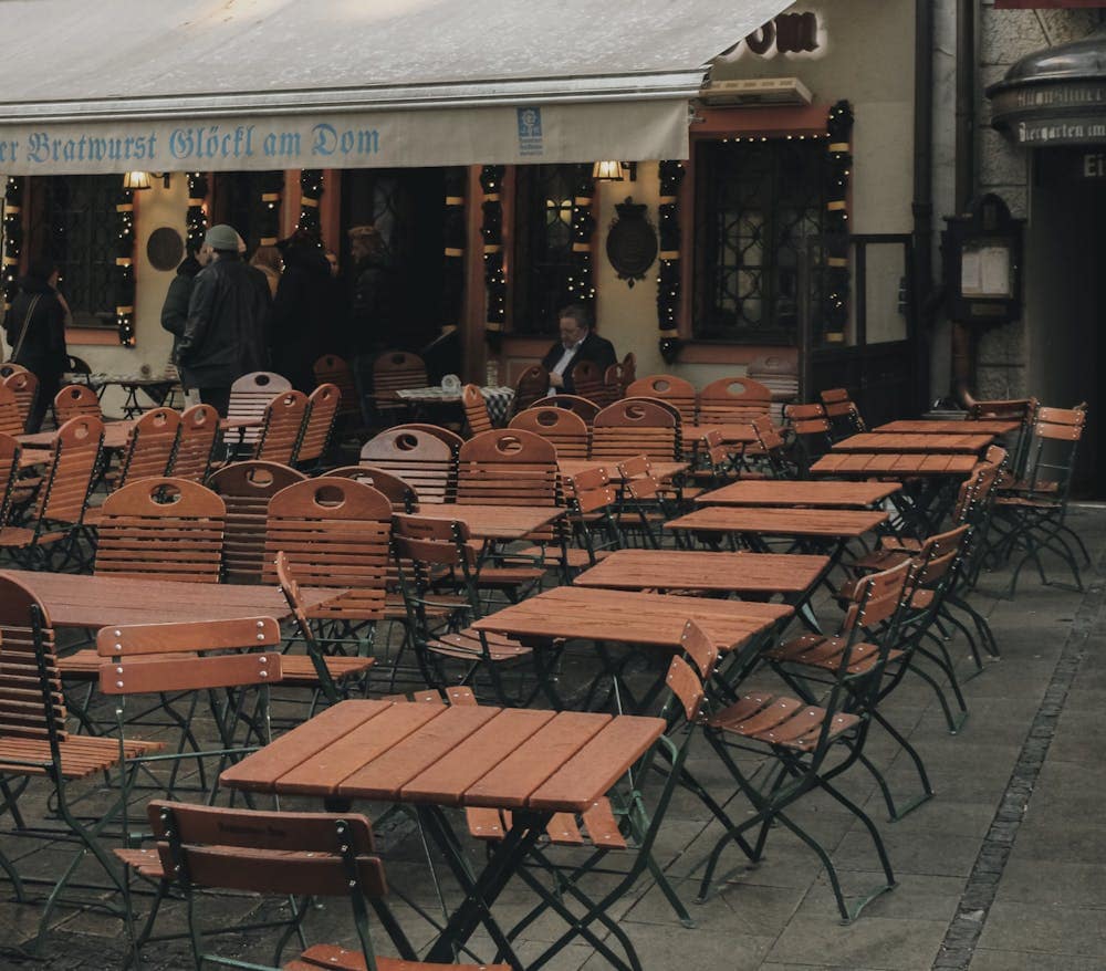 Cozy outdoor seating area of a traditional Munich cafe with wooden chairs and tables.